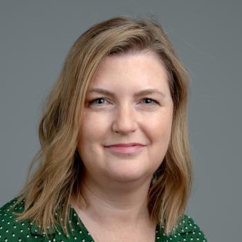 Kelli Schoen Headshot. Woman smiles at the camera with shoulder length blonde hair and green collared blouse.