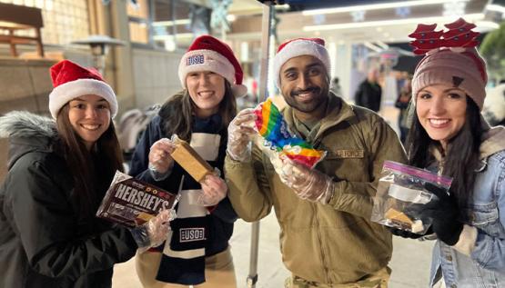 USO volunteers with serviceman holding ingredients for smores at holiday event