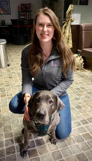 Shannon Hamelund kneeling beside dog inside USO building